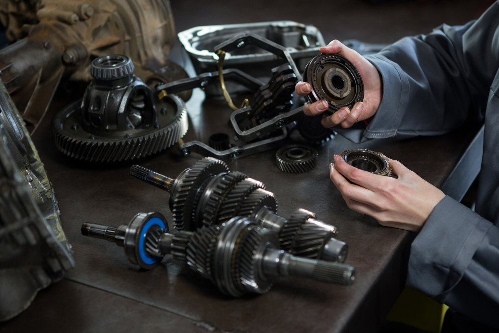 Technician inspecting industrial gears and mechanical spare parts on a workbench.